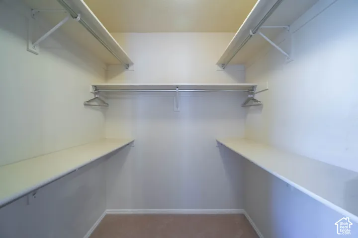 Spacious walk-in closet featuring dual clothing rods, shelving systems, and recessed lighting throughout