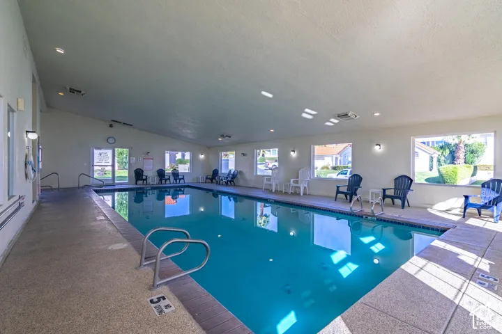 Indoor swimming pool with an angled ceiling, multiple windows, and recessed lighting