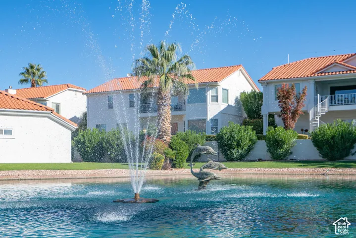 Waterfront property featuring a decorative fountain in the lagoon, mature palm trees, and lush landscaping
