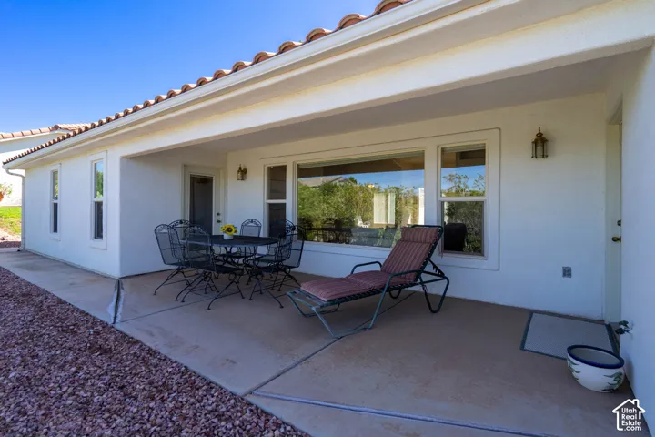 Covered patio featuring a concrete surface, exterior wall sconce, and large windows