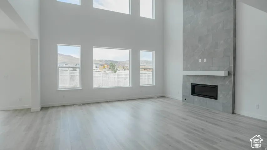 High ceilings, large windows, wood-finish flooring, and a floor-to-ceiling fireplace with an integrated mantel