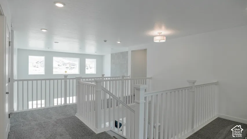 Carpeted upper landing with white baluster railings, recessed lighting, and a flush mount ceiling fixture