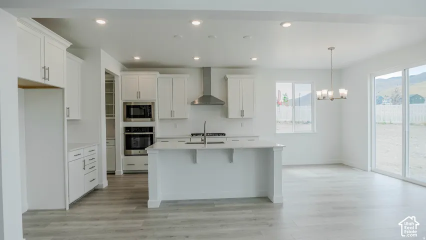Contemporary kitchen featuring white cabinetry, stainless steel appliances, a center island with countertop seating, wood-finish flooring, and sliding glass doors