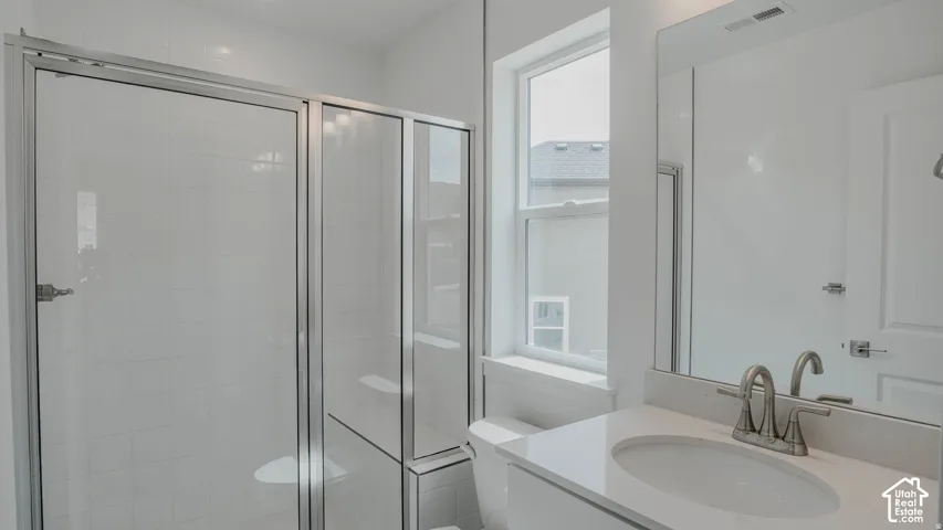 Glass-enclosed shower with white tiled walls, single-basin vanity with a light-toned countertop, brushed nickel faucet, and a large wall-mounted mirror