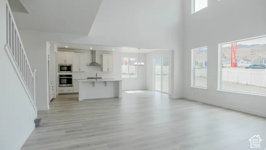 Open-concept living area with high ceilings, wood-finish flooring, a contemporary kitchen, and ample natural light from multiple windows