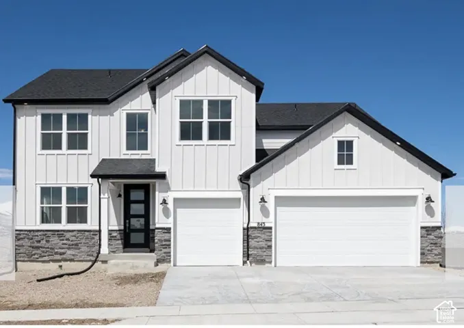 Two-story residence featuring white board and batten siding, dark shingle roofing, and a stone accent foundation