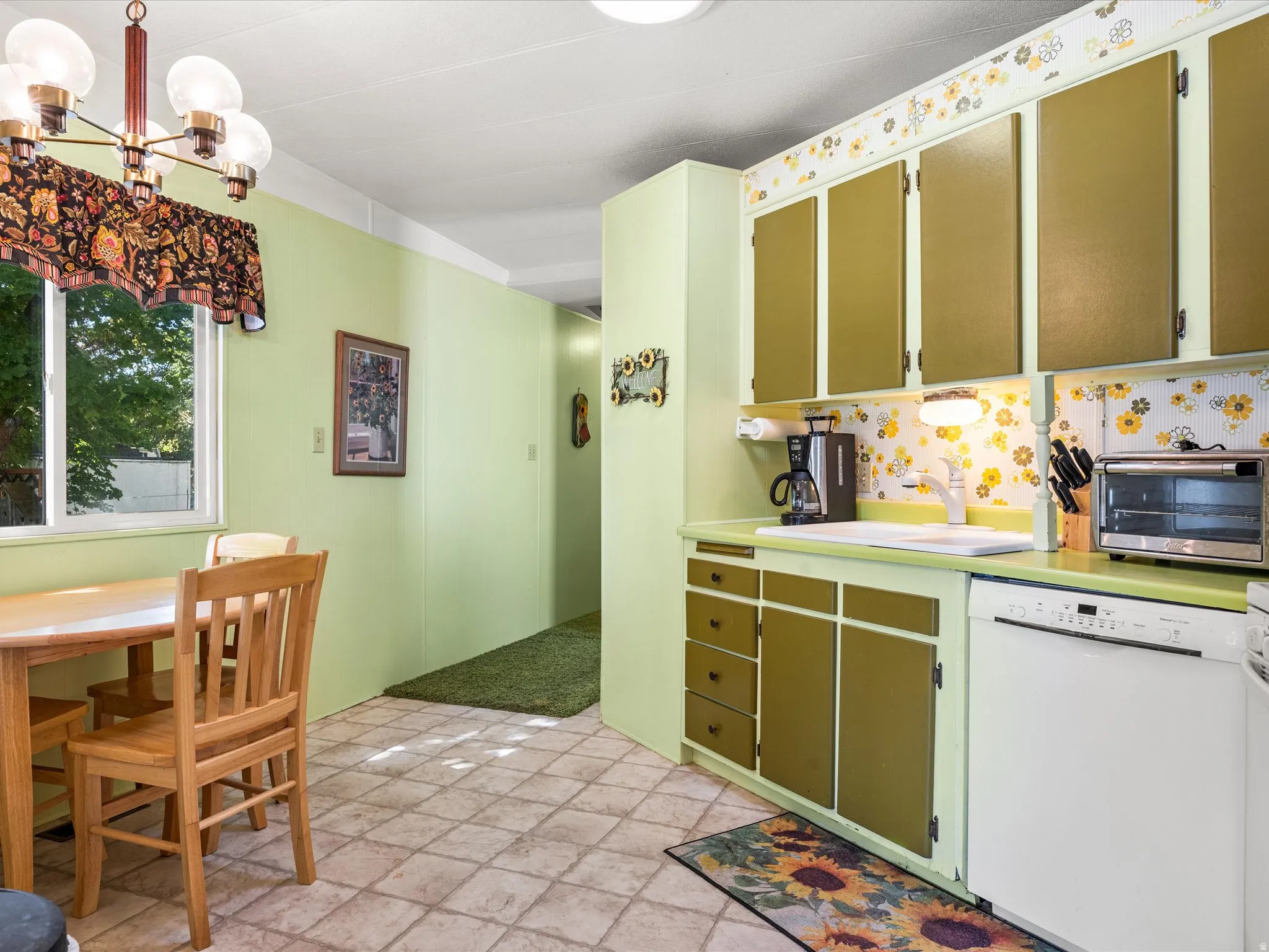 Kitchen area featuring olive green cabinetry, a white single-basin sink, and a built-in white dishwasher
