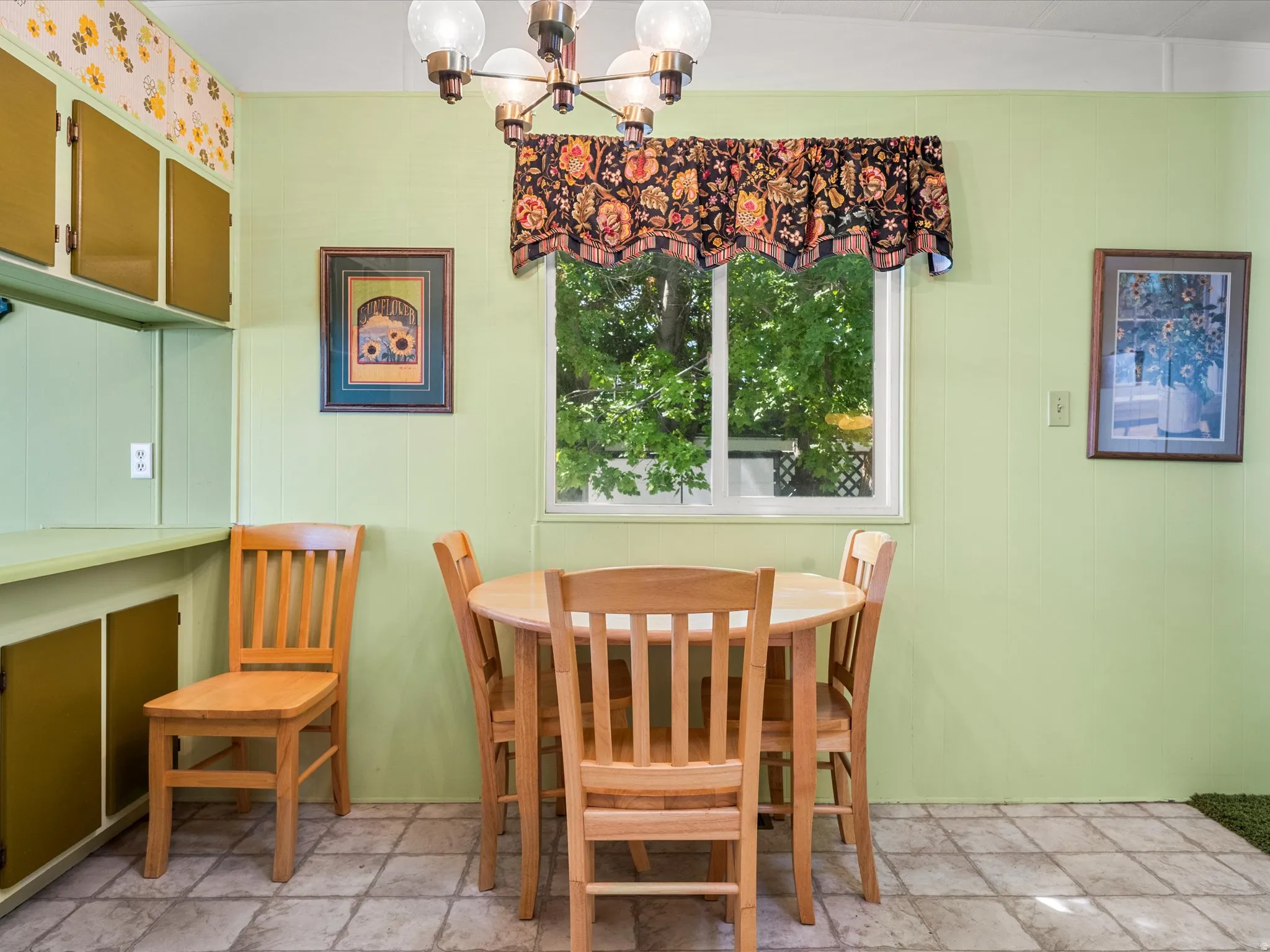 Built-in cabinetry with gold-toned doors, a window with exterior tree views, and an overhead light fixture