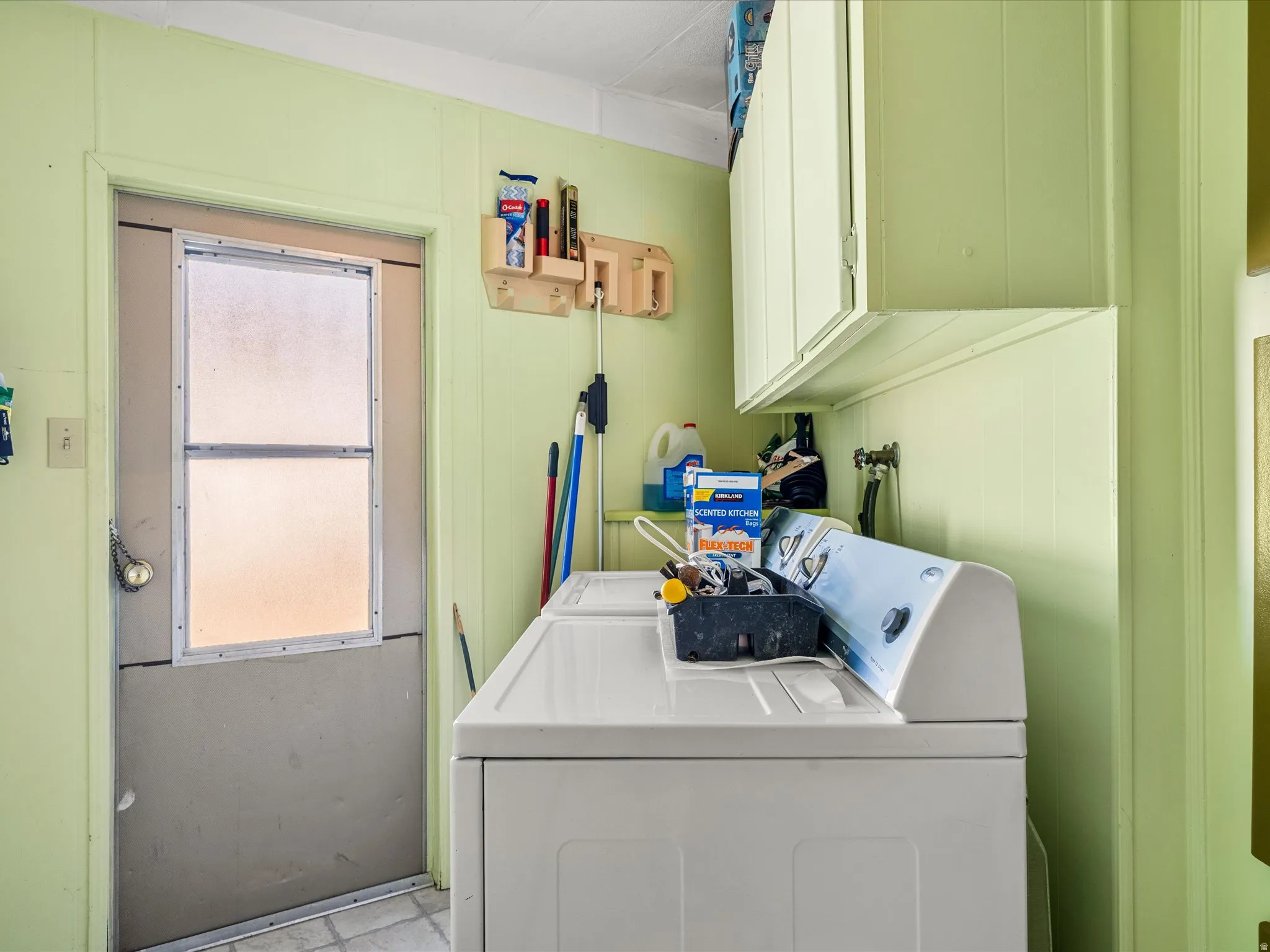 Utility area featuring a closed door, wall-mounted cabinetry, and a washer unit