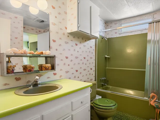 Bathroom with a built-in bathtub, a window, integrated sink, and white cabinetry