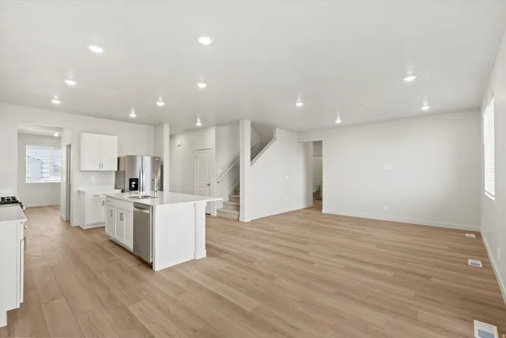Open-concept living space featuring wood-finish flooring, recessed lighting, and a kitchen island with integrated sink