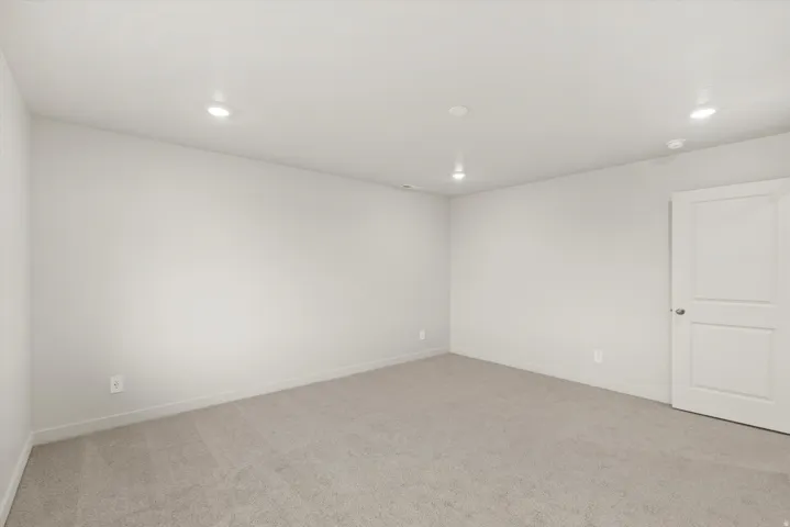 Neutral wall finishes, recessed lighting, light-toned carpet, and a two-panel interior door