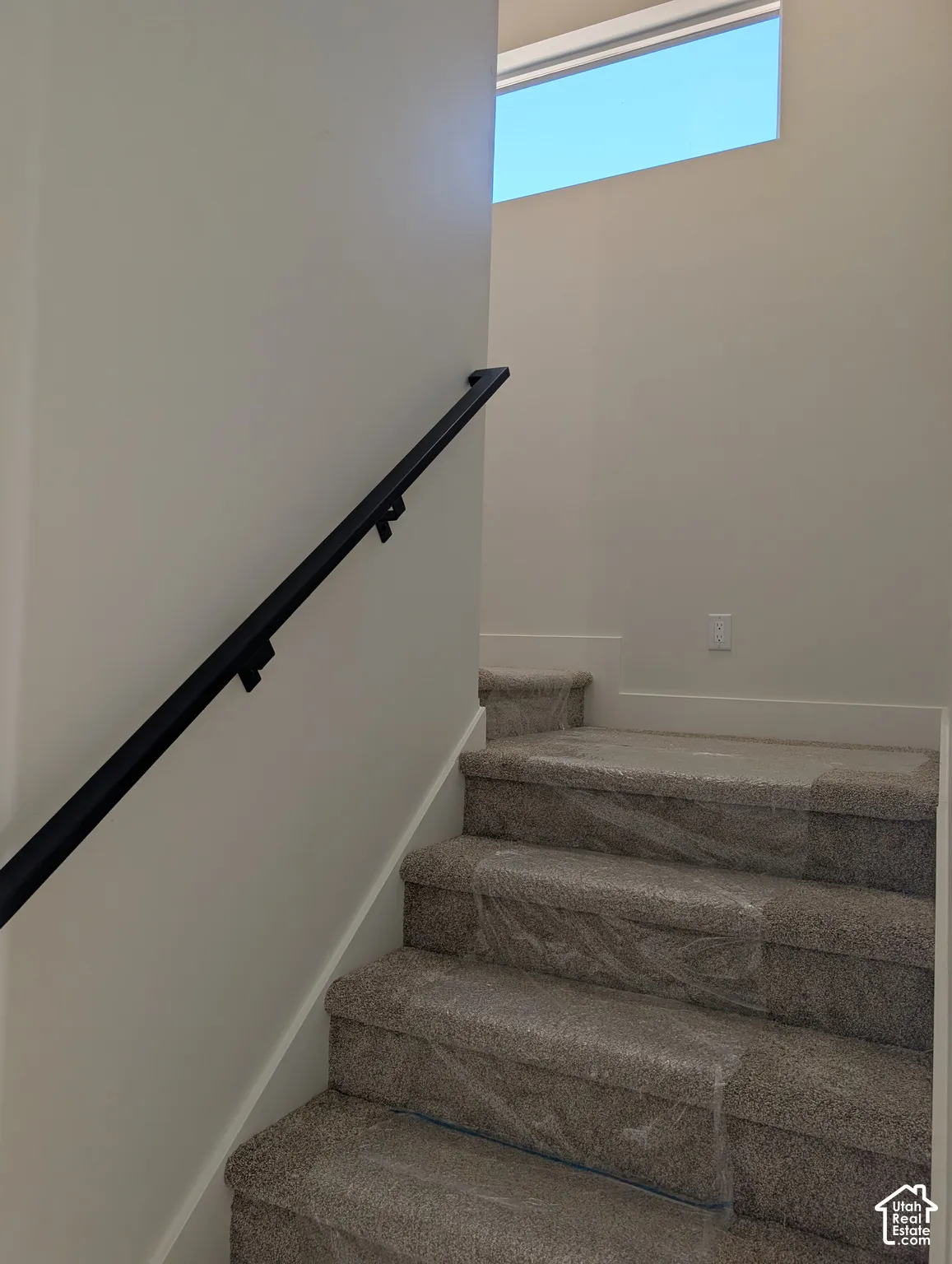 Staircase with a sleek black handrail and a high horizontal window