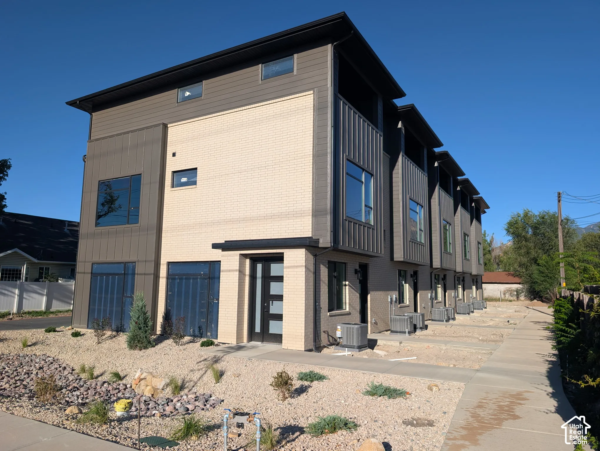 Contemporary architectural style featuring multi-tone exterior siding, a panel-style entry door, and dark-framed windows