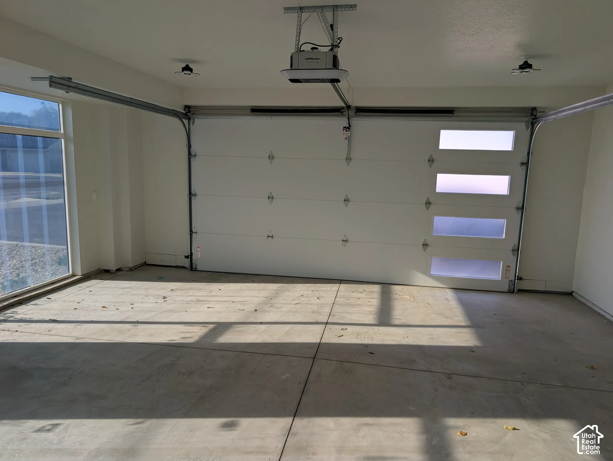Spacious garage featuring a modern overhead door with frosted glass panels, an automatic opener, and polished concrete flooring