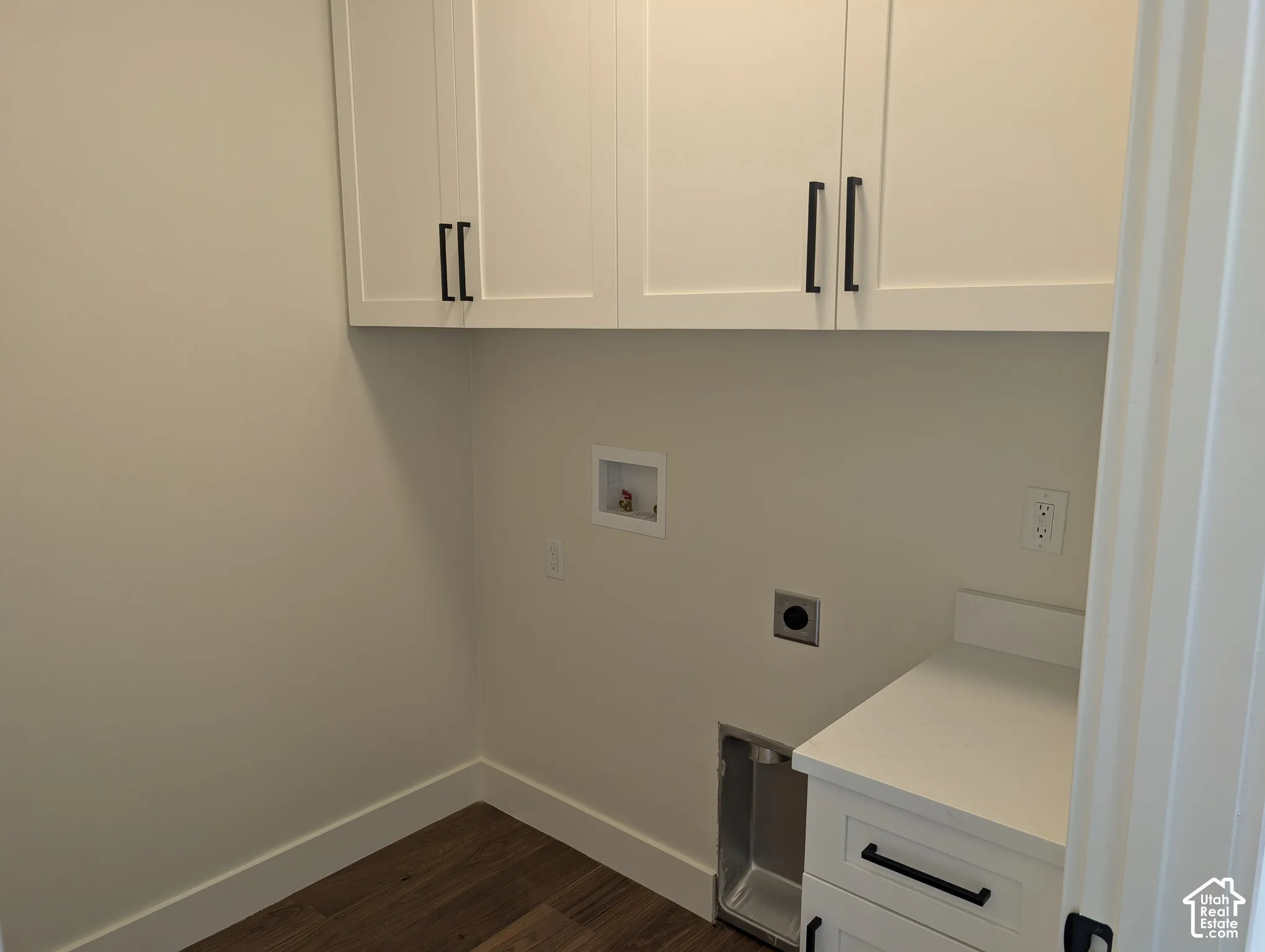 White shaker-style cabinetry with black hardware, wood-finish flooring, and a white countertop