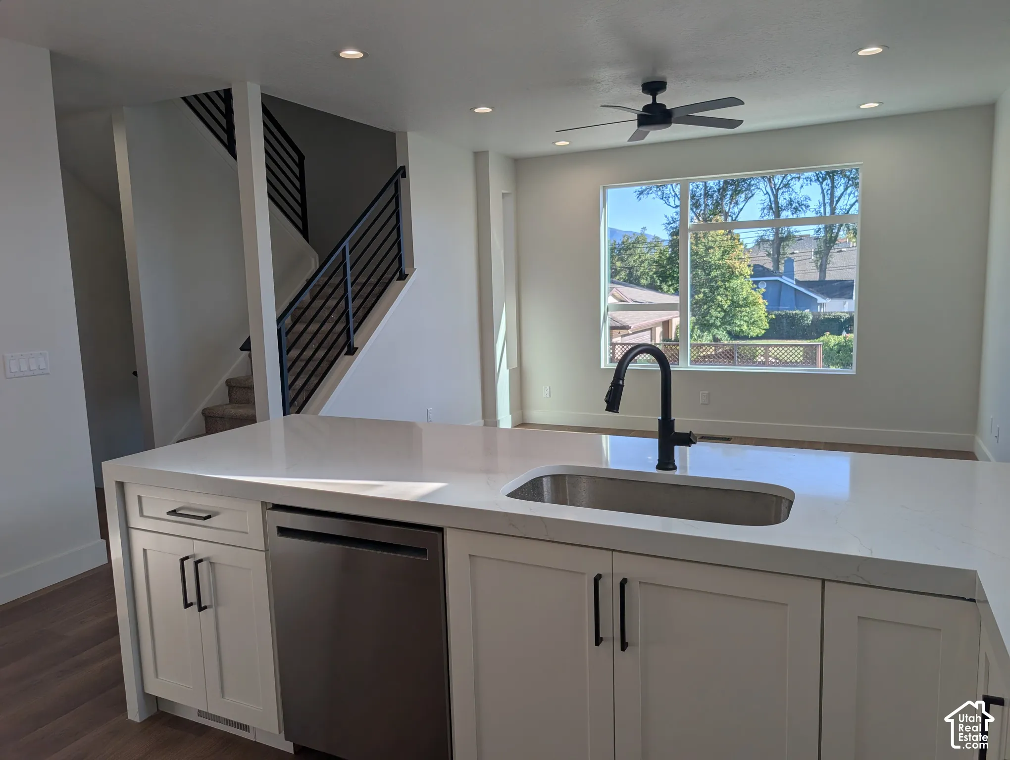 Kitchen island with white shaker cabinetry, stainless steel dishwasher, and an undermount sink with a matte black faucet
