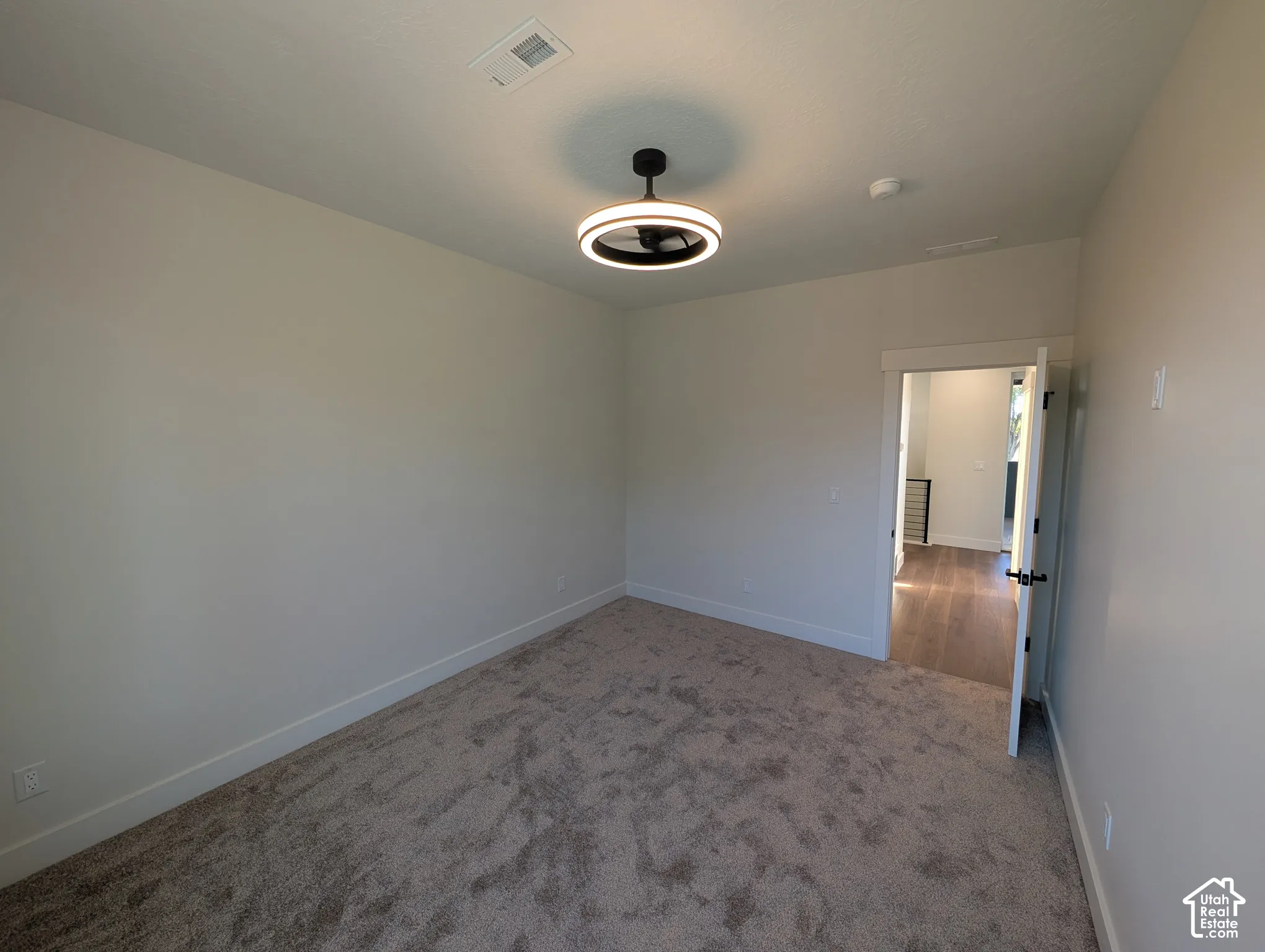 Neutral wall paint, textured carpet flooring, contemporary ceiling light fixture, white trim, and a white door with black hardware