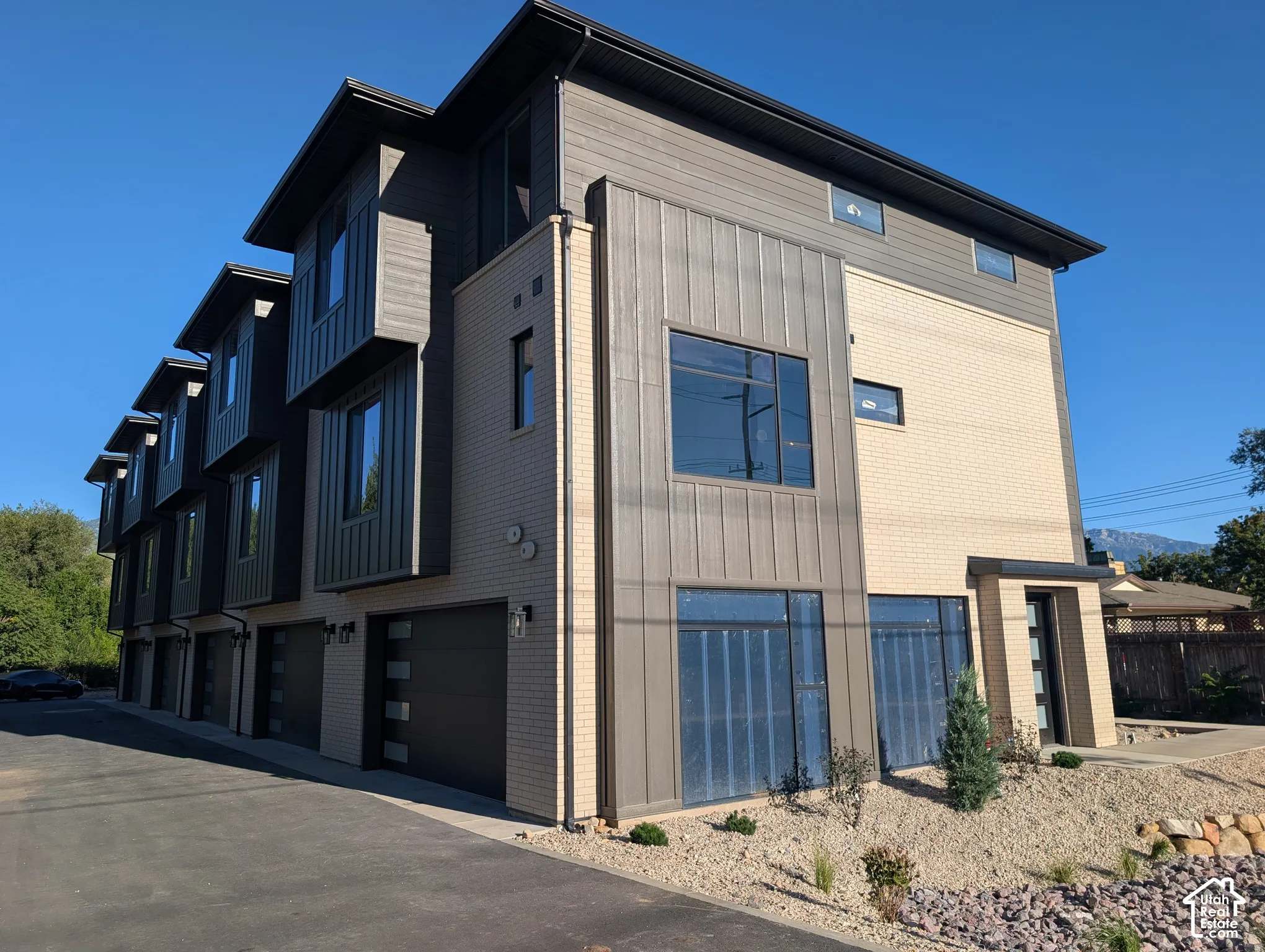Modern townhome featuring a multi-textured facade with brick, horizontal siding, and vertical metal paneling