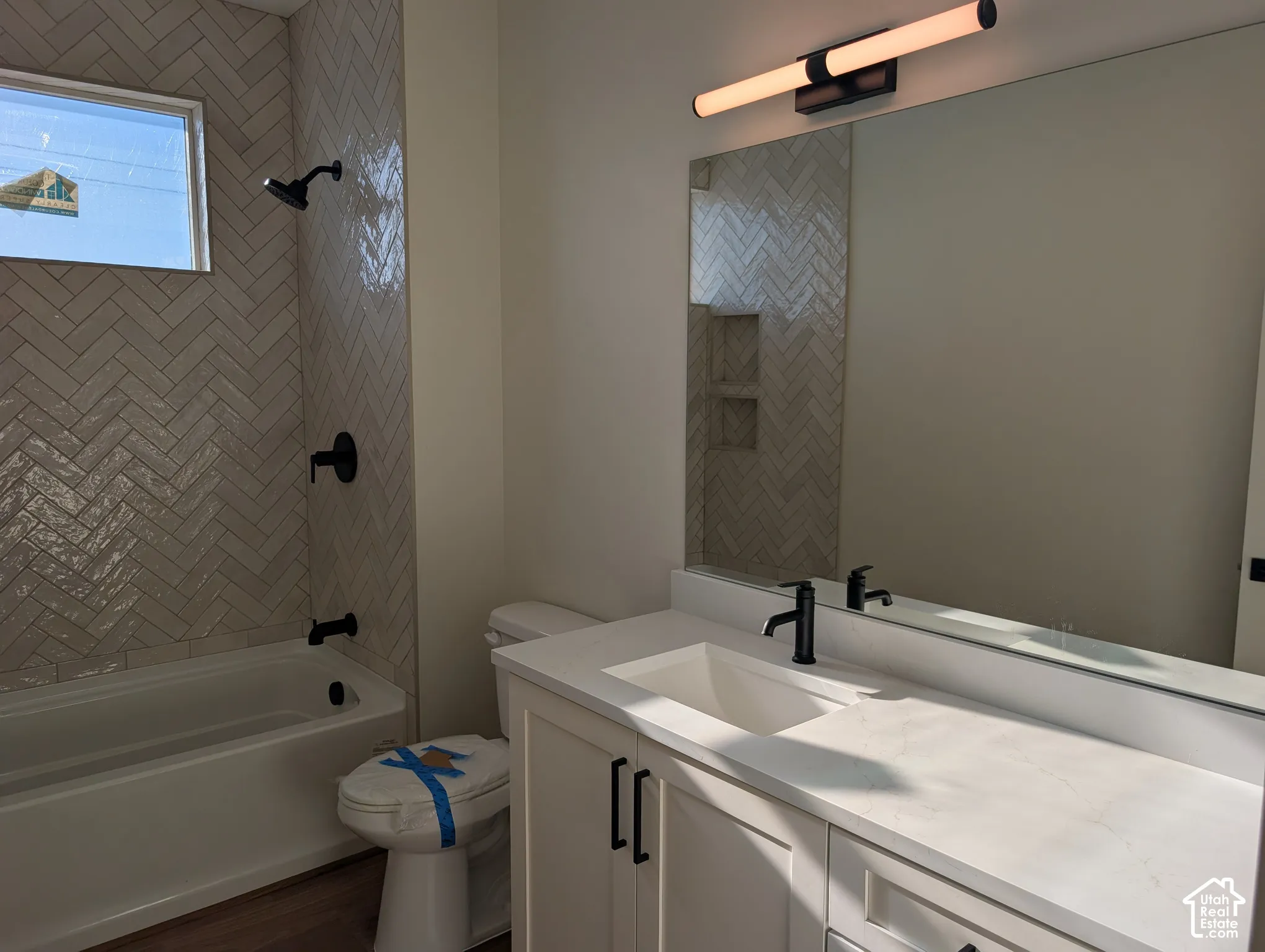 White vanity with black cabinet pulls, integrated rectangular sink, and light-toned countertop