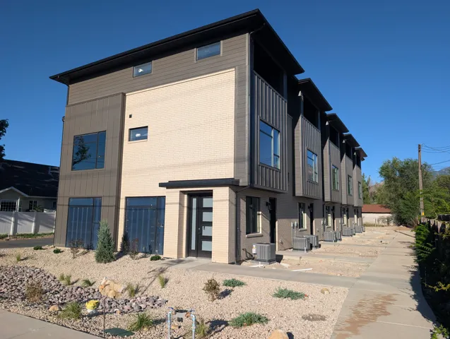Contemporary architectural style featuring multi-tone exterior siding, a panel-style entry door, and dark-framed windows