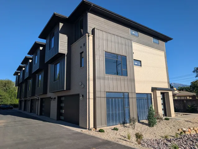 Modern townhome featuring a multi-textured facade with brick, horizontal siding, and vertical metal paneling