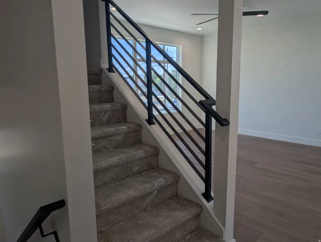 Staircase with contemporary black metal railing and carpeted treads