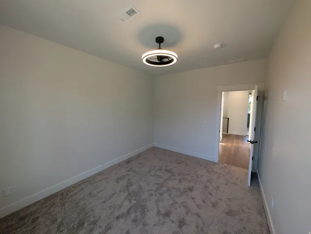 Neutral wall paint, textured carpet flooring, contemporary ceiling light fixture, white trim, and a white door with black hardware