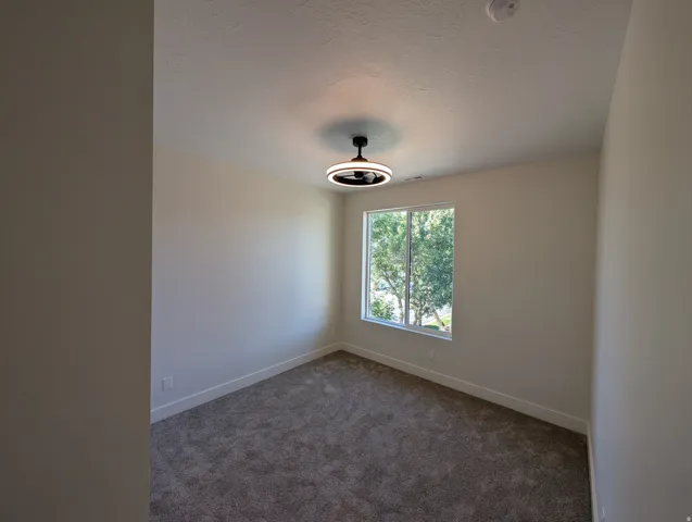Neutral wall paint, textured ceiling, broad window, recessed lighting fixture, and carpeted flooring