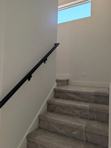 Staircase with a sleek black handrail and a high horizontal window