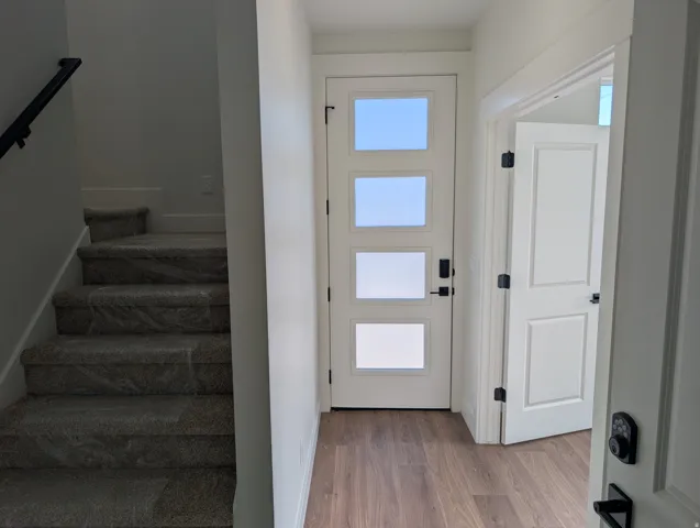 Wood-finish flooring, white paneled interior doors, and a front entry door with privacy glass
