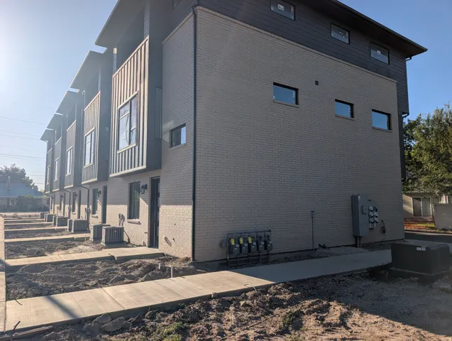 Contemporary townhome exterior featuring light-colored brick siding, dark vertical panel accents, and multiple windows