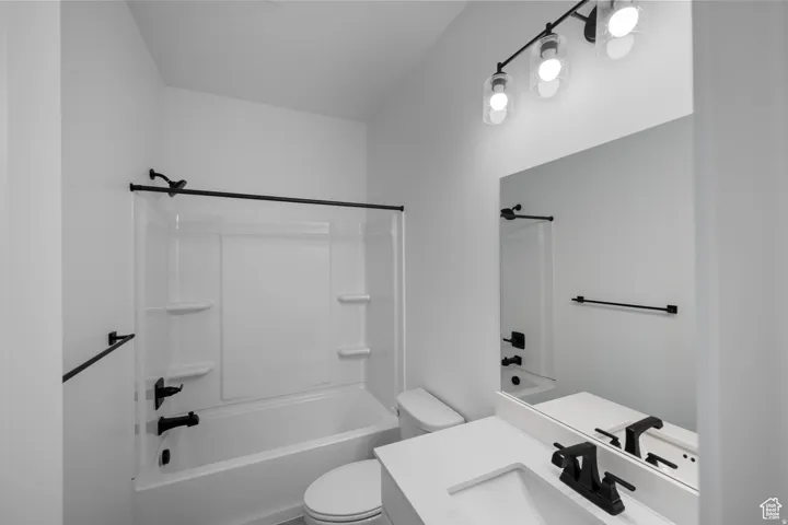 Bathtub with integrated shower, white vanity with integrated sink, black hardware, wall-mounted mirror, and contemporary vanity lighting