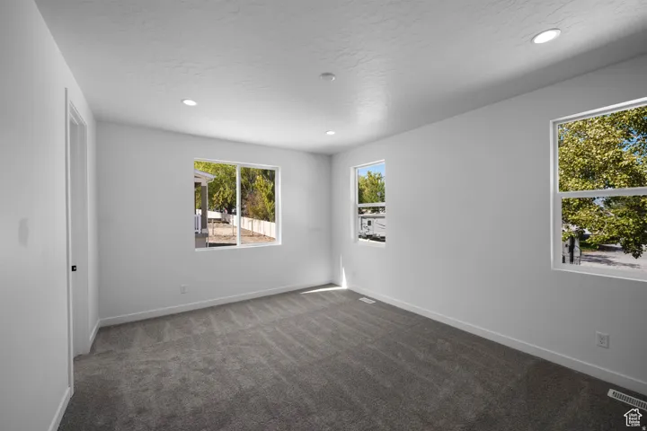 Spacious room with plush gray carpeting, white walls, and multiple windows