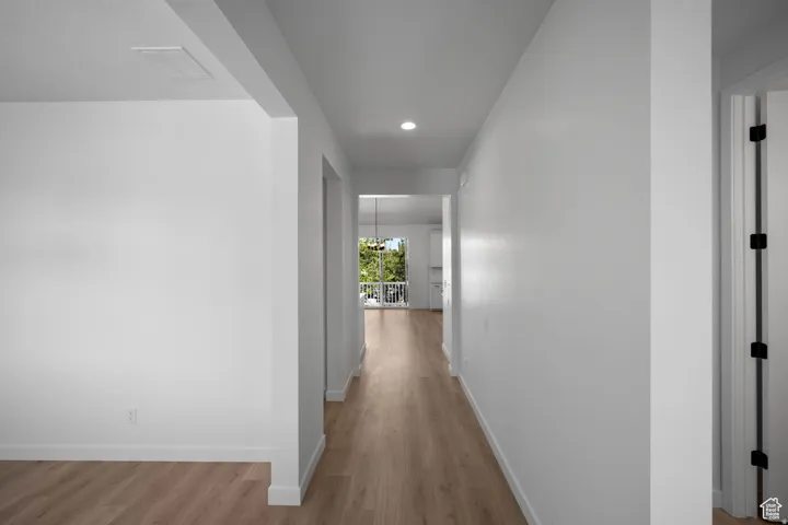 Hallway with wood-finish flooring, recessed lighting, and white walls