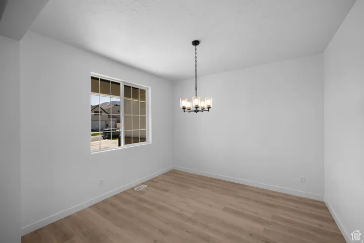 Spacious interior with neutral white walls, wood-finish flooring, and a contemporary chandelier