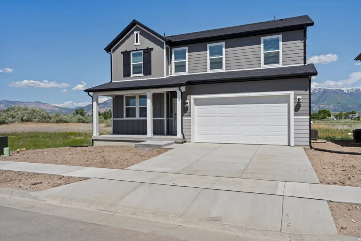 Two-story residence featuring a covered entry porch, two-car garage, and gray horizontal siding