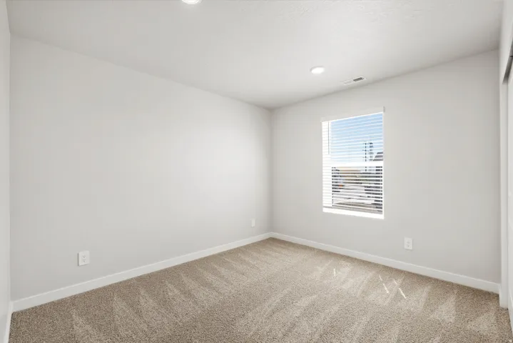 Recessed lighting, light-toned walls, patterned carpeting, and a window with blinds