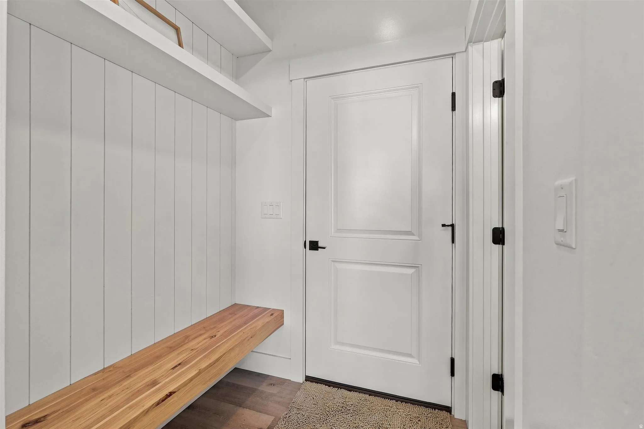 Mudroom featuring shiplap wall paneling, a built-in wood bench, and two floating shelves