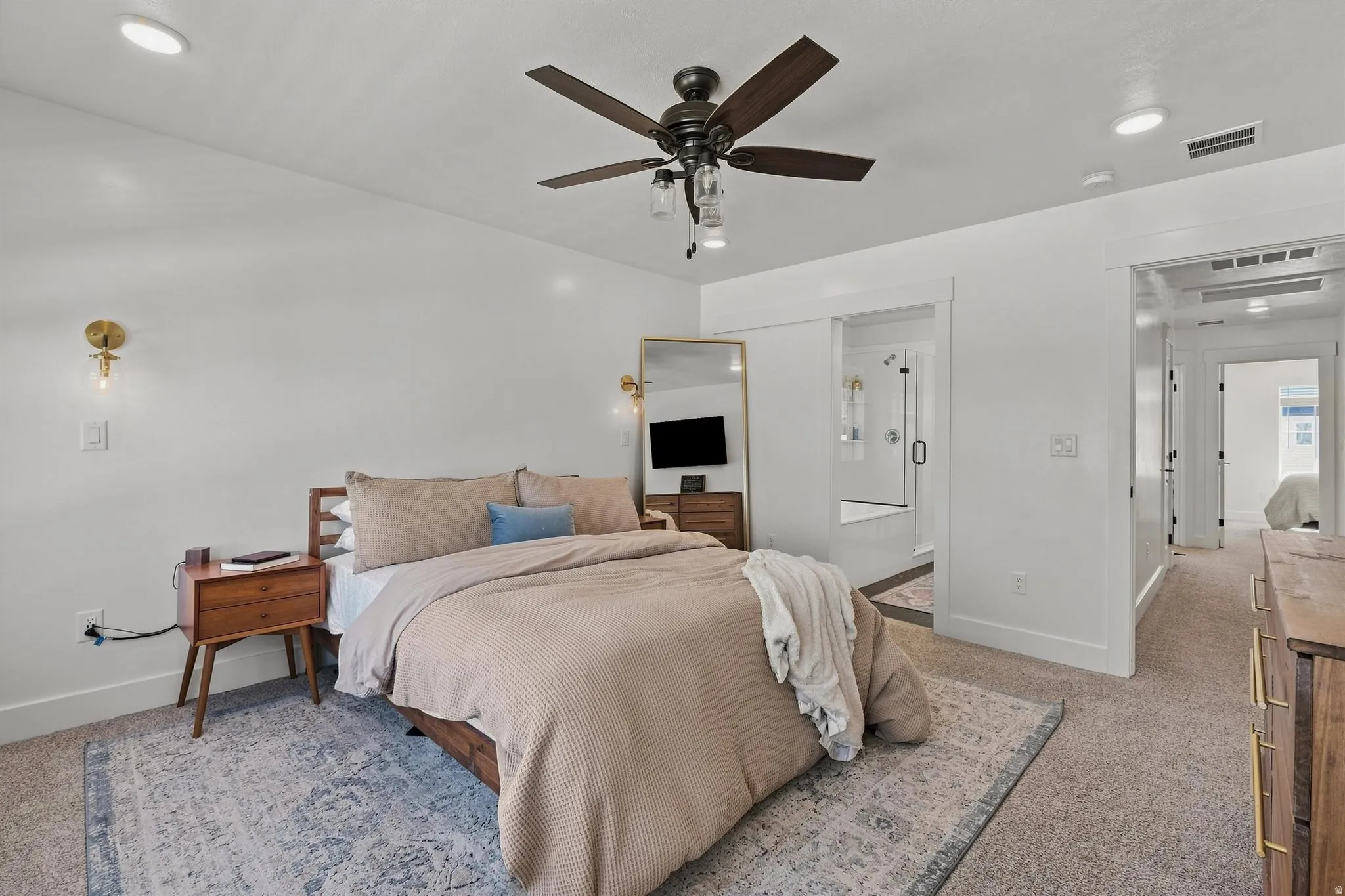 Recessed lighting, ceiling fan with integrated light, wall-mounted sconces, wide doorway, and carpet flooring