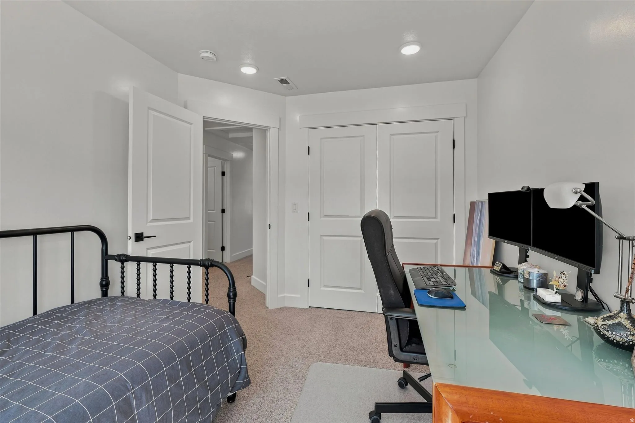 White interior doors with black hardware, recessed ceiling lighting, and light-colored carpet flooring