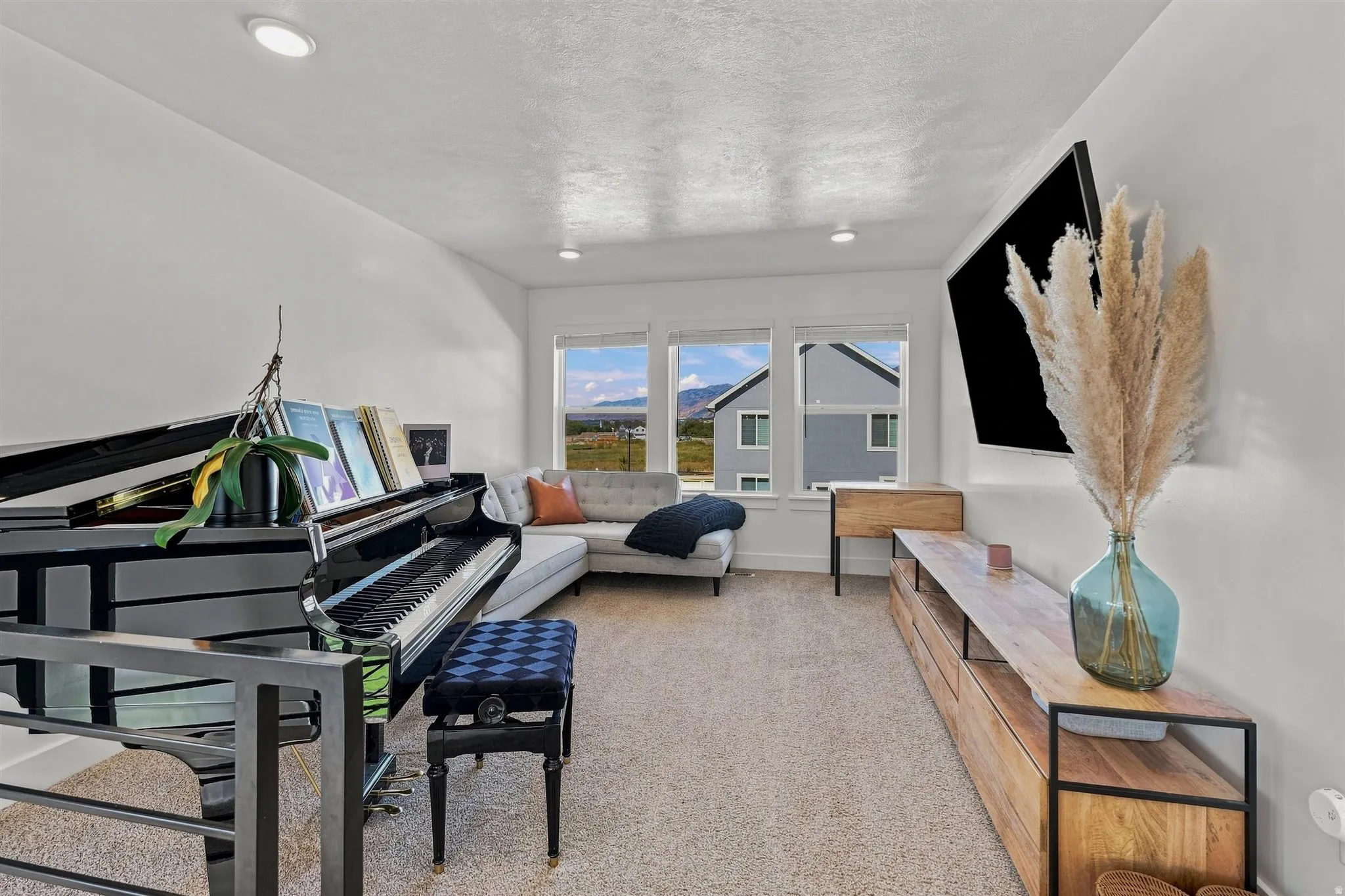 Recessed lighting, light-toned carpeting, and a built-in media console with wood-finish top