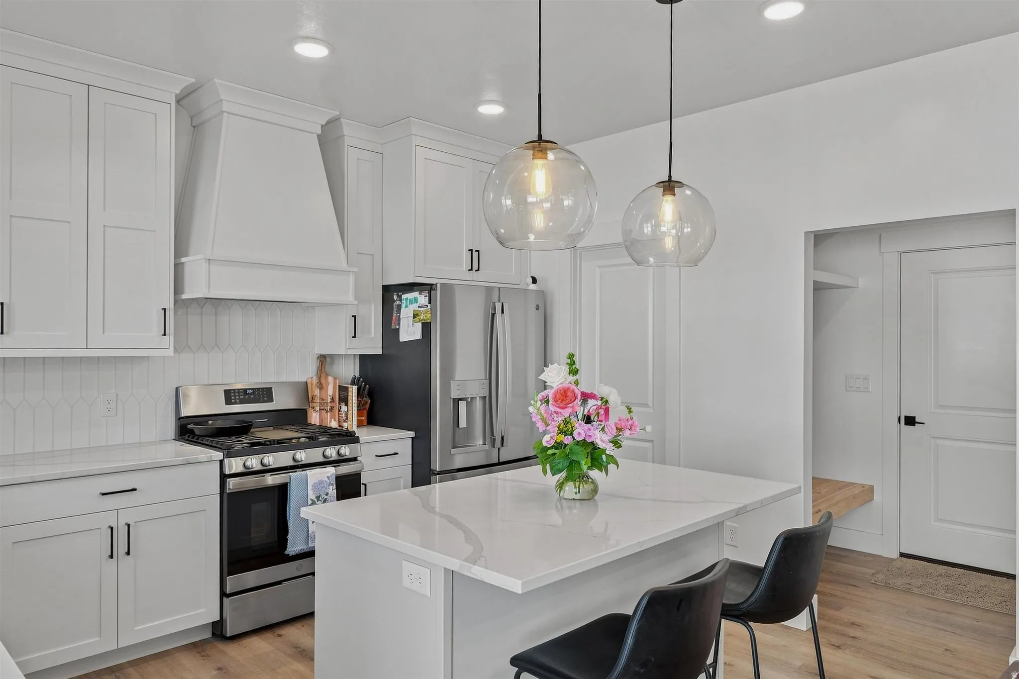 Modern kitchen featuring light cabinetry, quartz countertops, stainless steel appliances, and wood-finish flooring