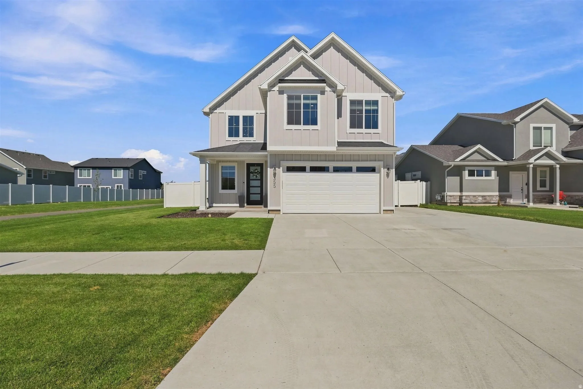 Light gray vertical siding exterior with white trim, a covered entry, an attached garage, and a concrete driveway