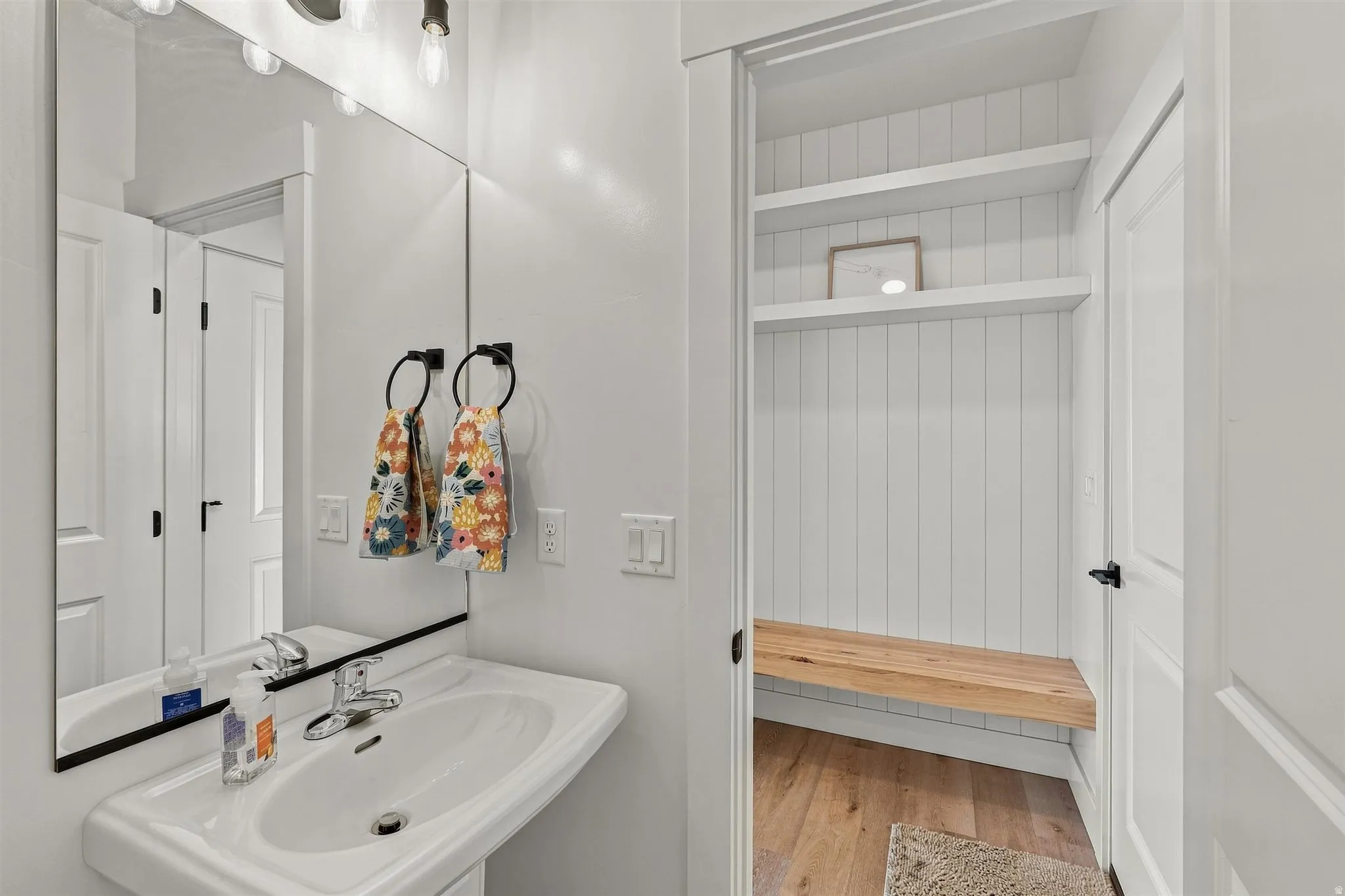 Pedestal sink with chrome fixtures and a rectangular mirror
