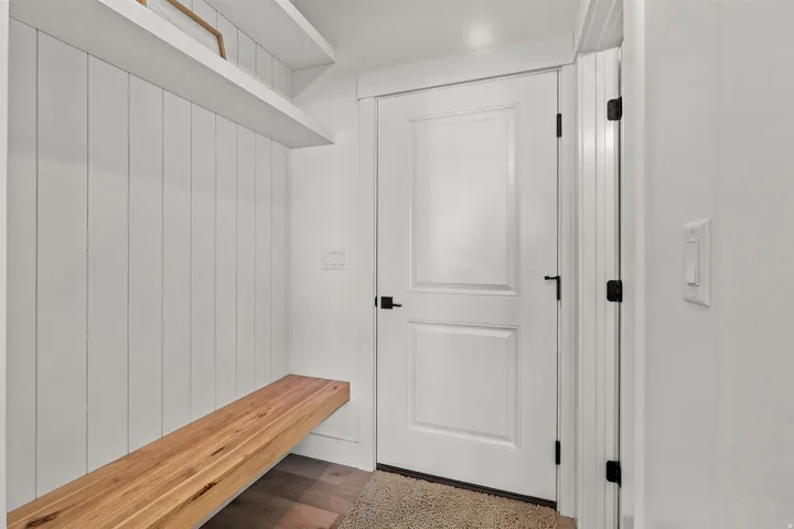 Mudroom featuring shiplap wall paneling, a built-in wood bench, and two floating shelves