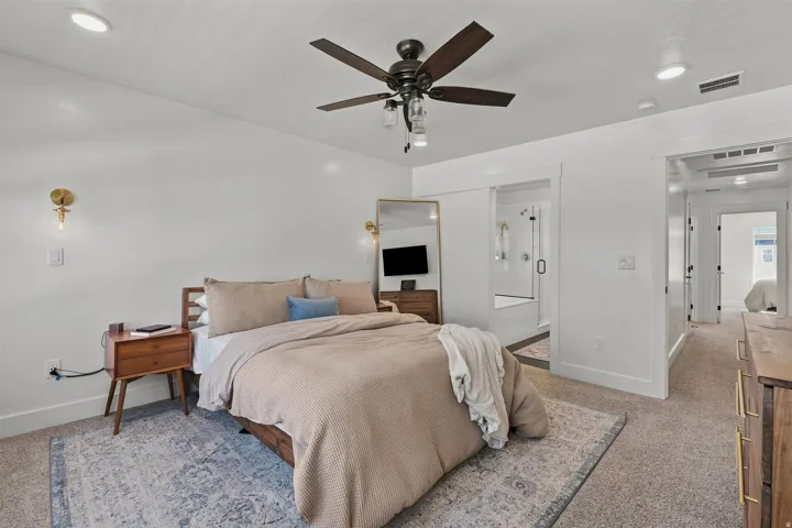 Recessed lighting, ceiling fan with integrated light, wall-mounted sconces, wide doorway, and carpet flooring