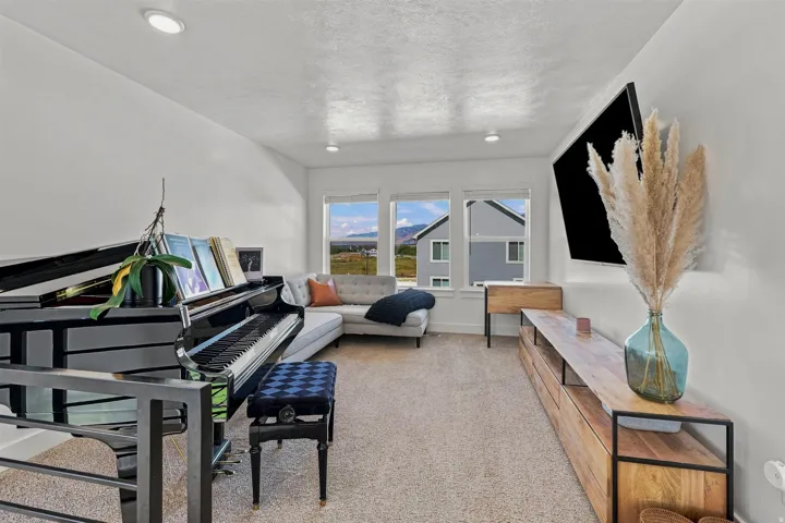 Recessed lighting, light-toned carpeting, and a built-in media console with wood-finish top