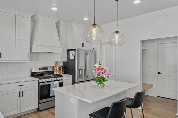 Modern kitchen featuring light cabinetry, quartz countertops, stainless steel appliances, and wood-finish flooring