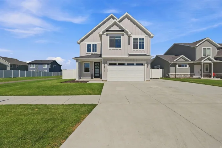 Light gray vertical siding exterior with white trim, a covered entry, an attached garage, and a concrete driveway